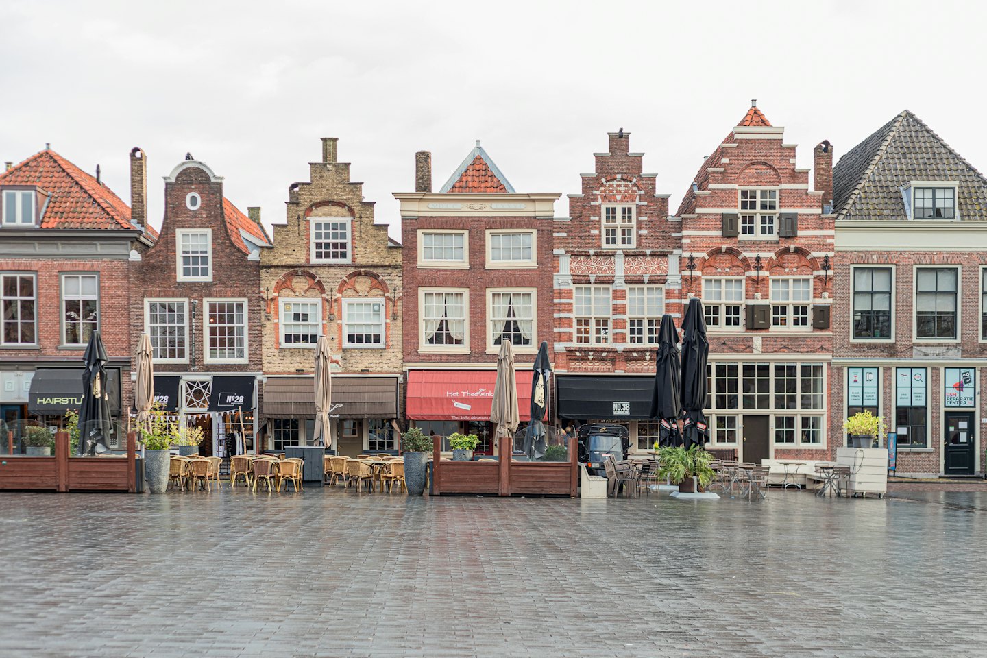 Historischer europäischer Stadtplatz mit Backsteingebäuden und leeren Café-Sitzplätzen.